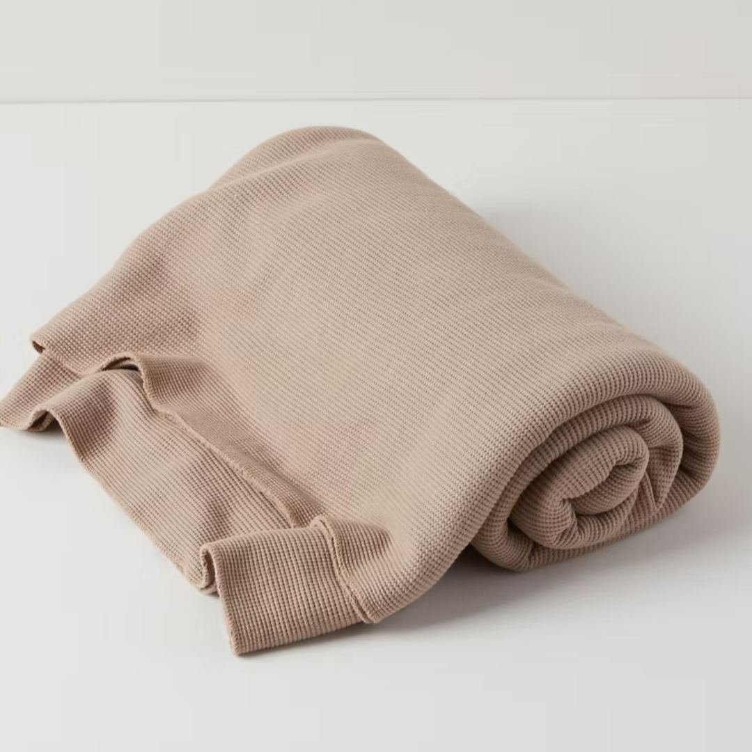 תקריב של טקסטורת וופל על שמיכת כותנה אורגנית בצבע חום שוקו