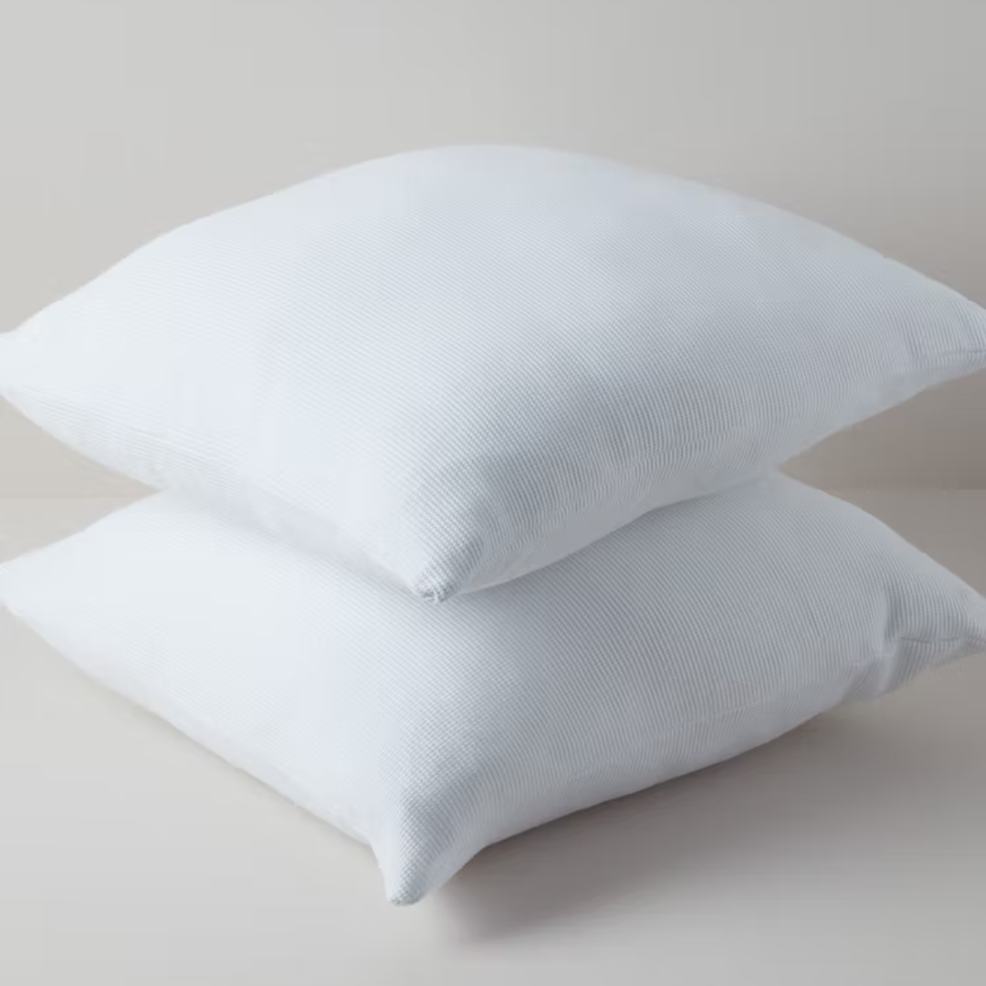 כריות נוי וופל מכותנה אורגנית מסודרות בשורה בצבע לבן שלג.