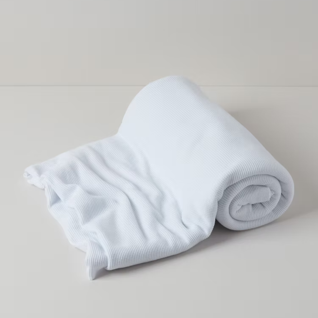 תקריב של טקסטורת וופל על שמיכת כותנה אורגנית בצבע לבן שלג